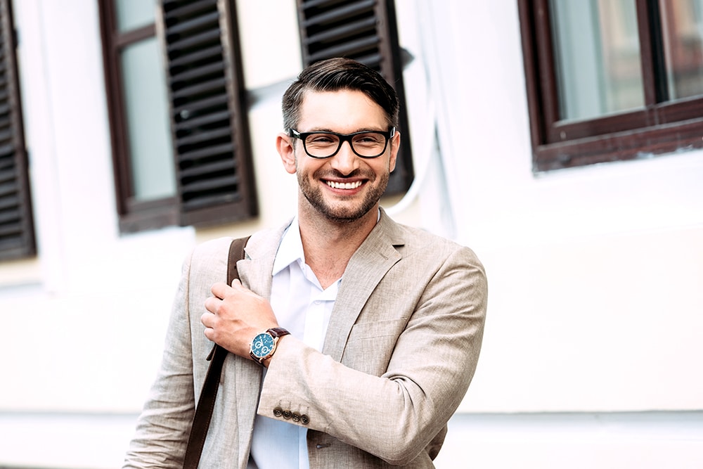 Smiling businessman in glasses and wristwatch on street
