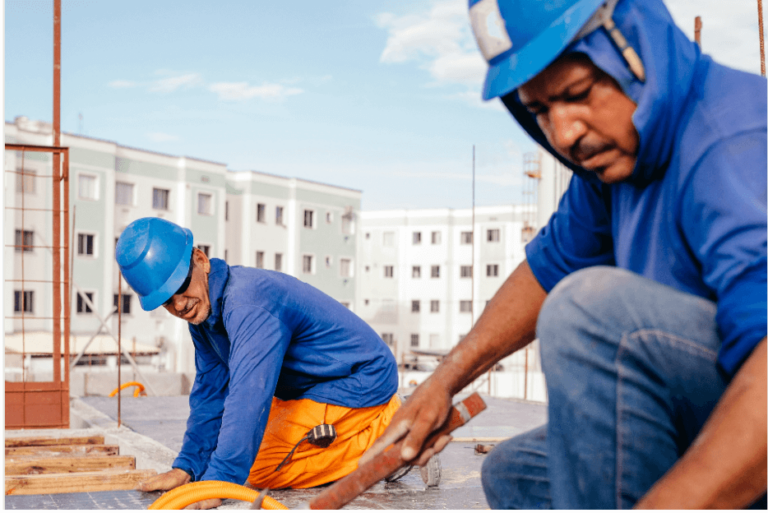 Roofers with hardhats on a roof on a sunny day.